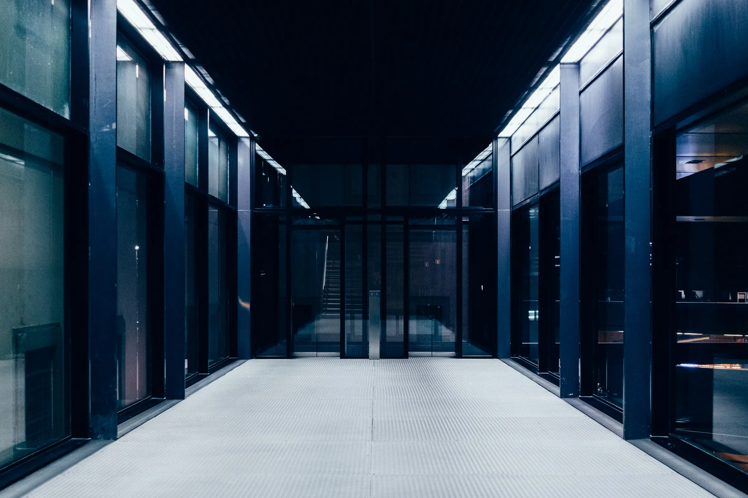 A long, dark, lit hallway of glass doors