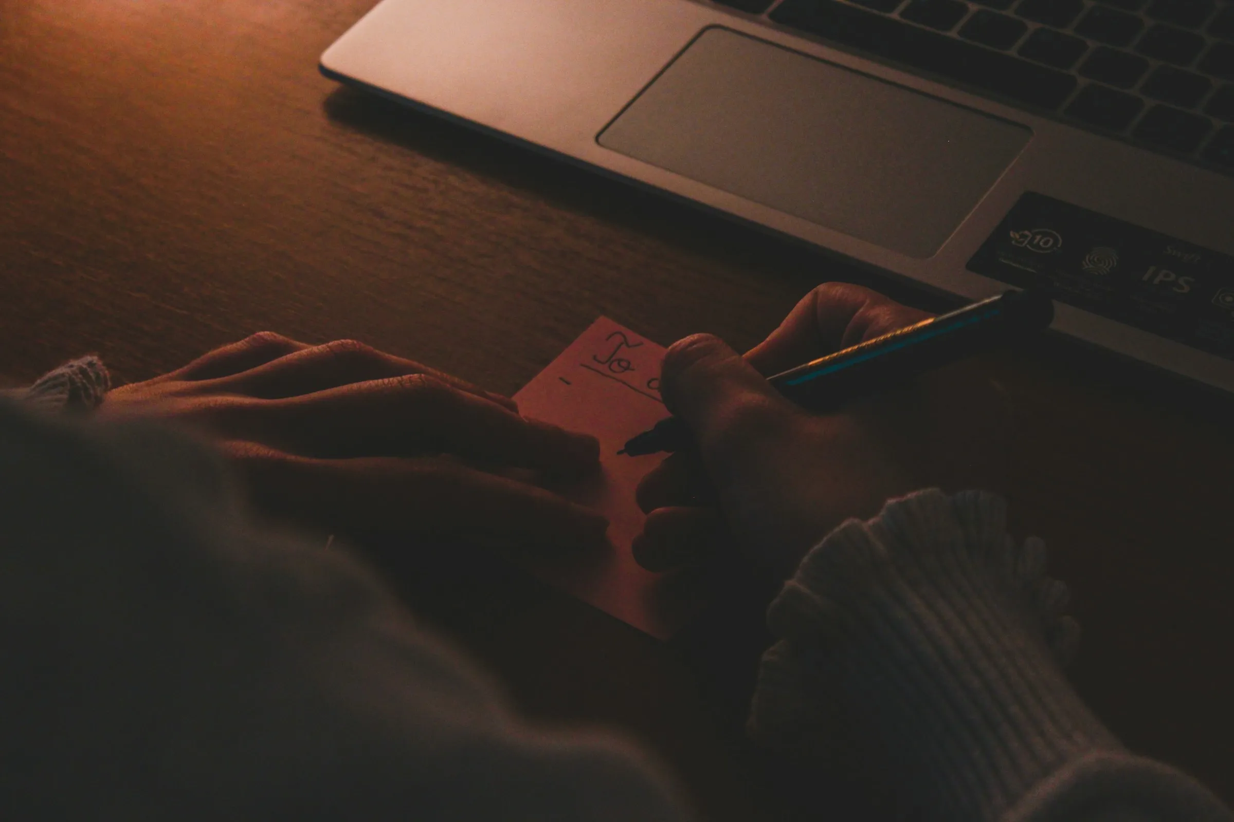 A hand holding a card beside an open laptop