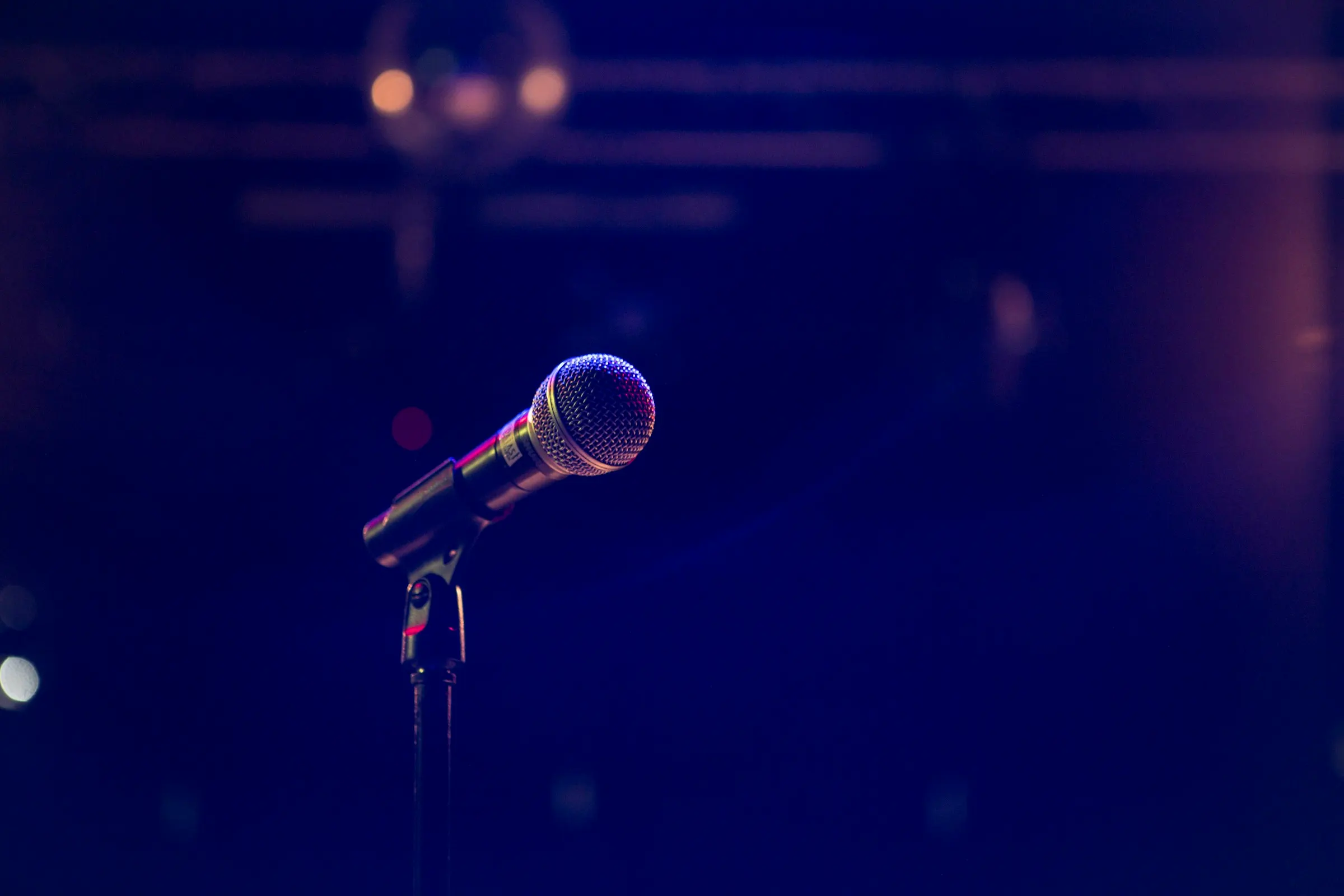 A microphone on a stand under deep blue stage light