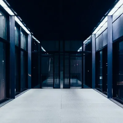 A long, dark, lit hallway of glass doors