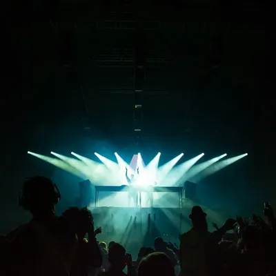 A crowd facing teal stage lights