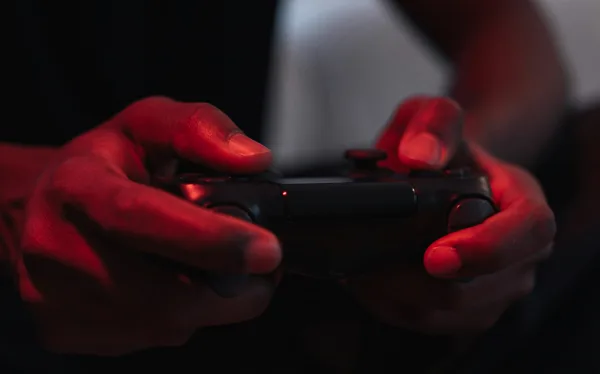Hands gripping a game controller in red light
